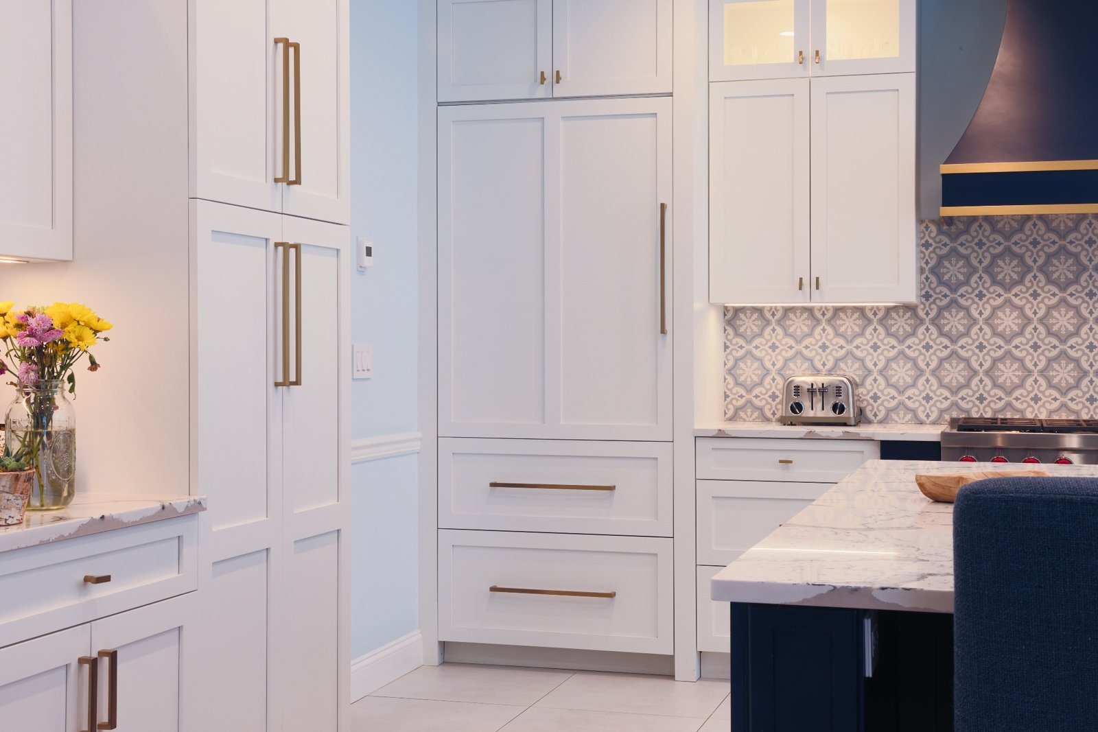 Integrated refrigerator with custom cabinet panels and gold hardware in Nesconset NY kitchen.