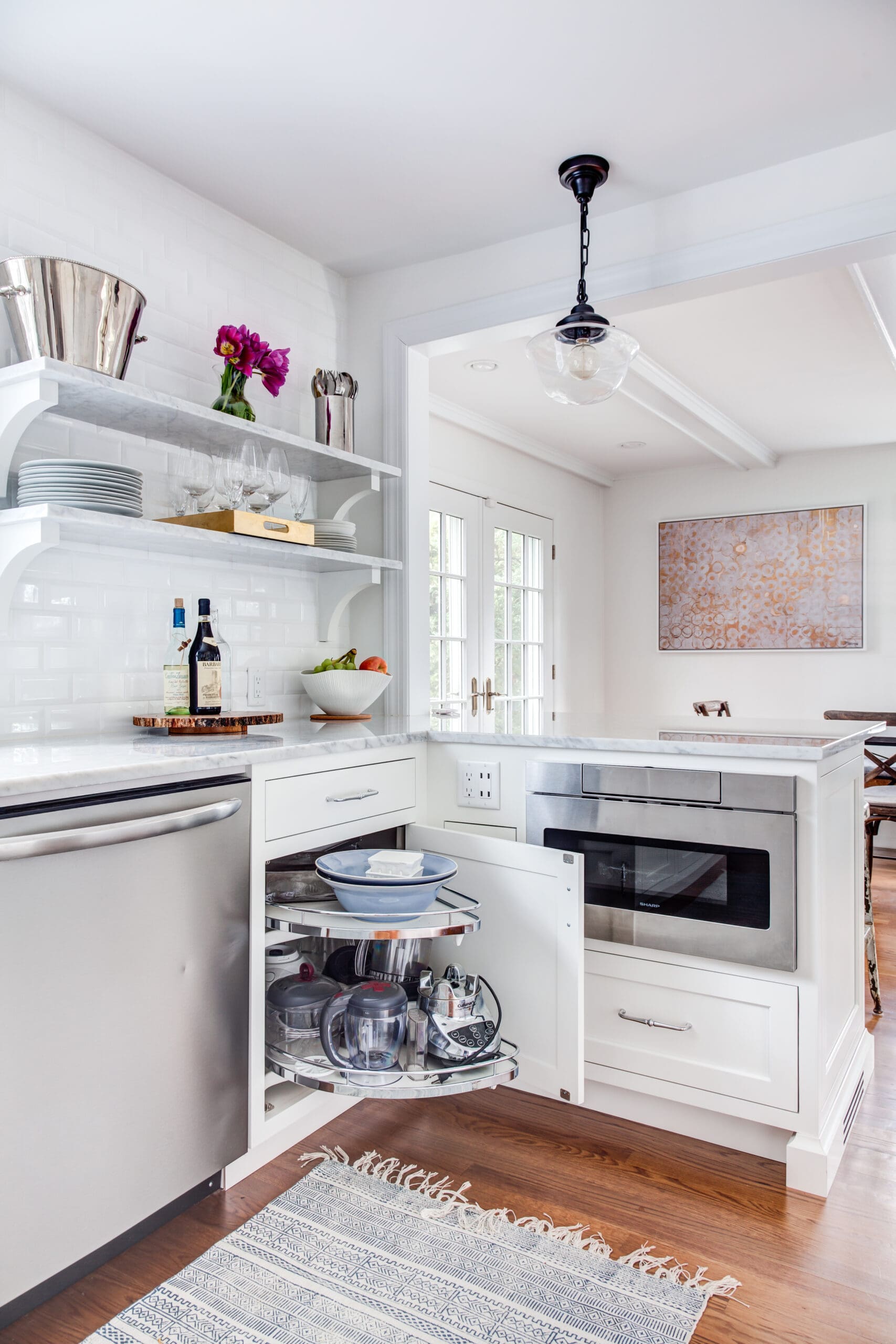 small kitchen cabinetry. White painted cabinets. Showing a corner cabinet pull-out and microwave built into the lower cabinets.