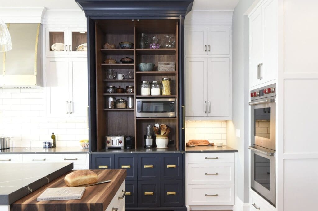 High end kitchen custom storage cabinet with dark blue drawers, walnut interior shelving, glass display cabinets, and integrated appliance storage.