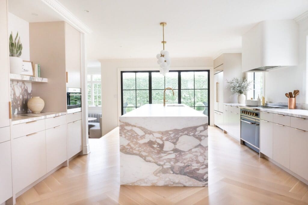 Two-tone custom kitchen cabinetry in New Jersey with a natural wood island, glass-front cabinets, skylight, and paneled storage for a high end kitchen design.