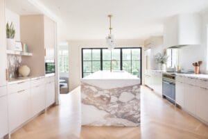 Two-tone custom kitchen cabinetry in New Jersey with a natural wood island, glass-front cabinets, skylight, and paneled storage for a high end kitchen design.